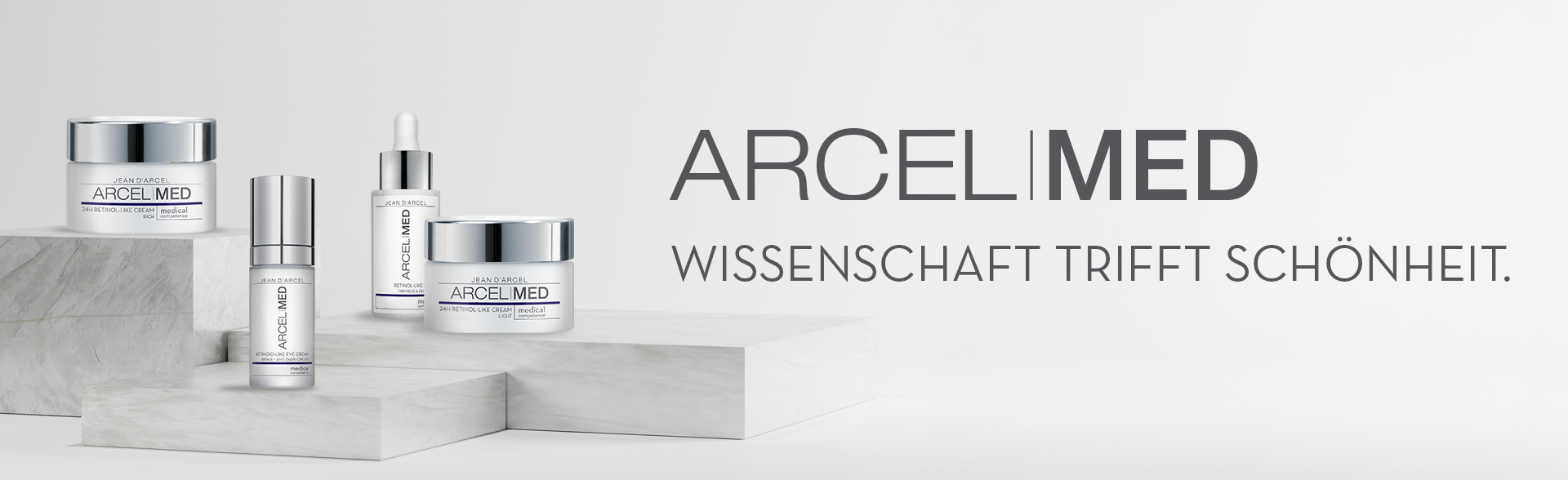 Produkte der Jean D'Arcel ARCELMED Pflegelinie auf weißen Podesten. Daneben der Schriftzug „ARCELMED – Wissenschaft trifft Schönheit.“
