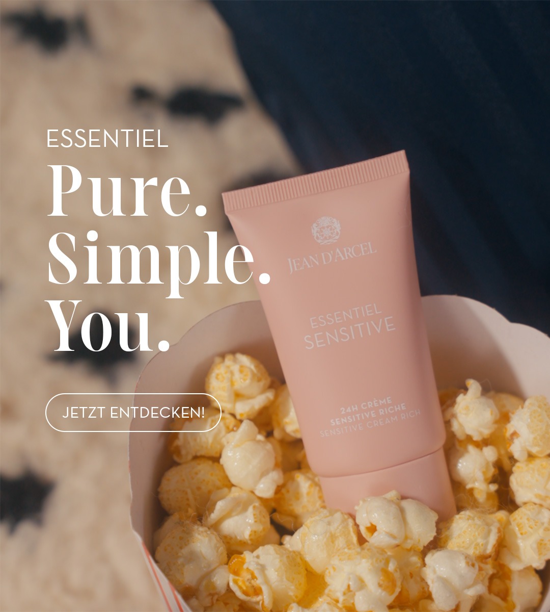 „Rosafarbene Jean-D’Arcel-Creme in einer Popcornschale mit dem Slogan ‚Pure. Simple. You.‘.“
